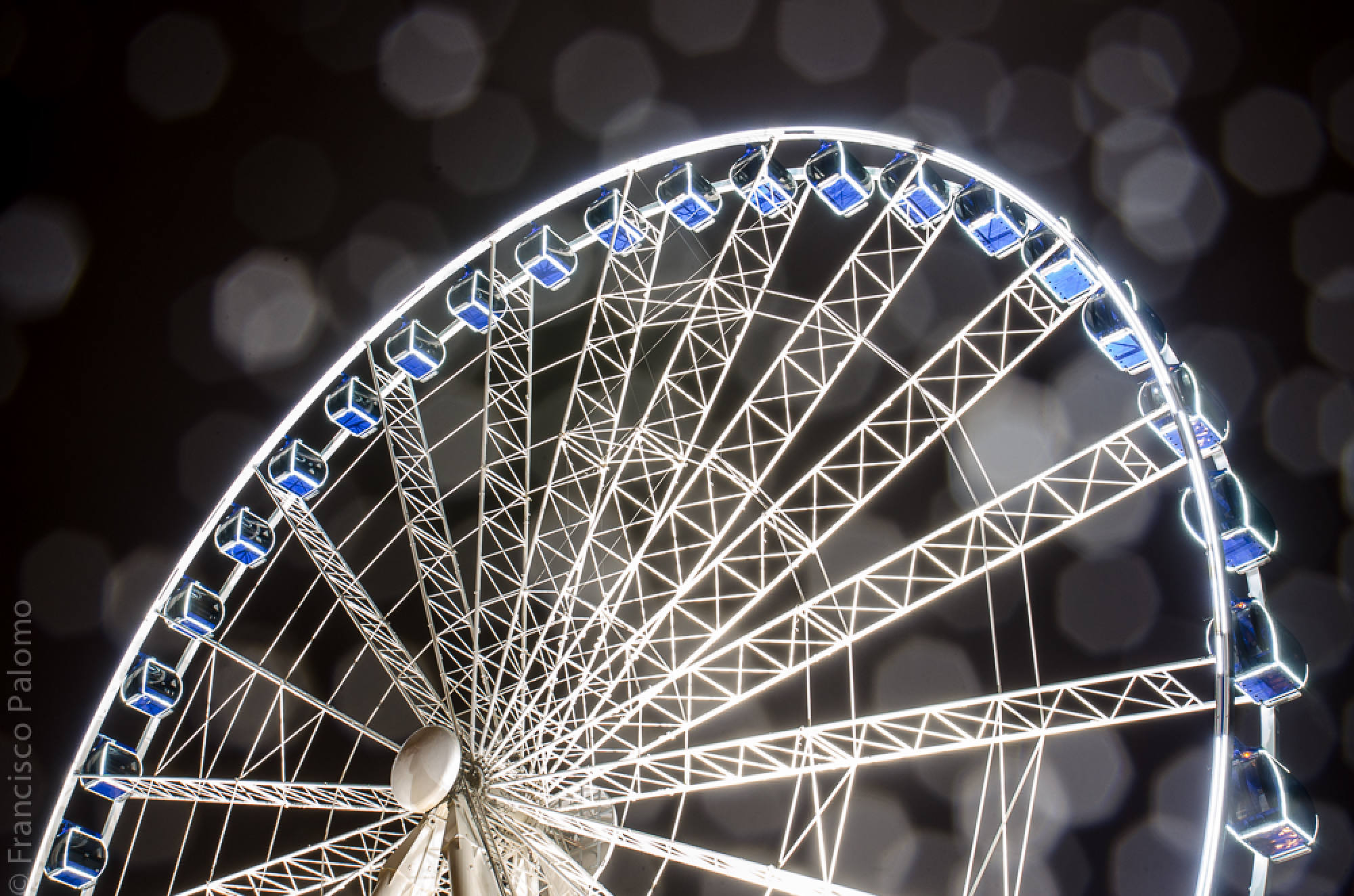 Beleuchtetes Riesenrad vor unscharfen Lichtpunkten in der Nacht