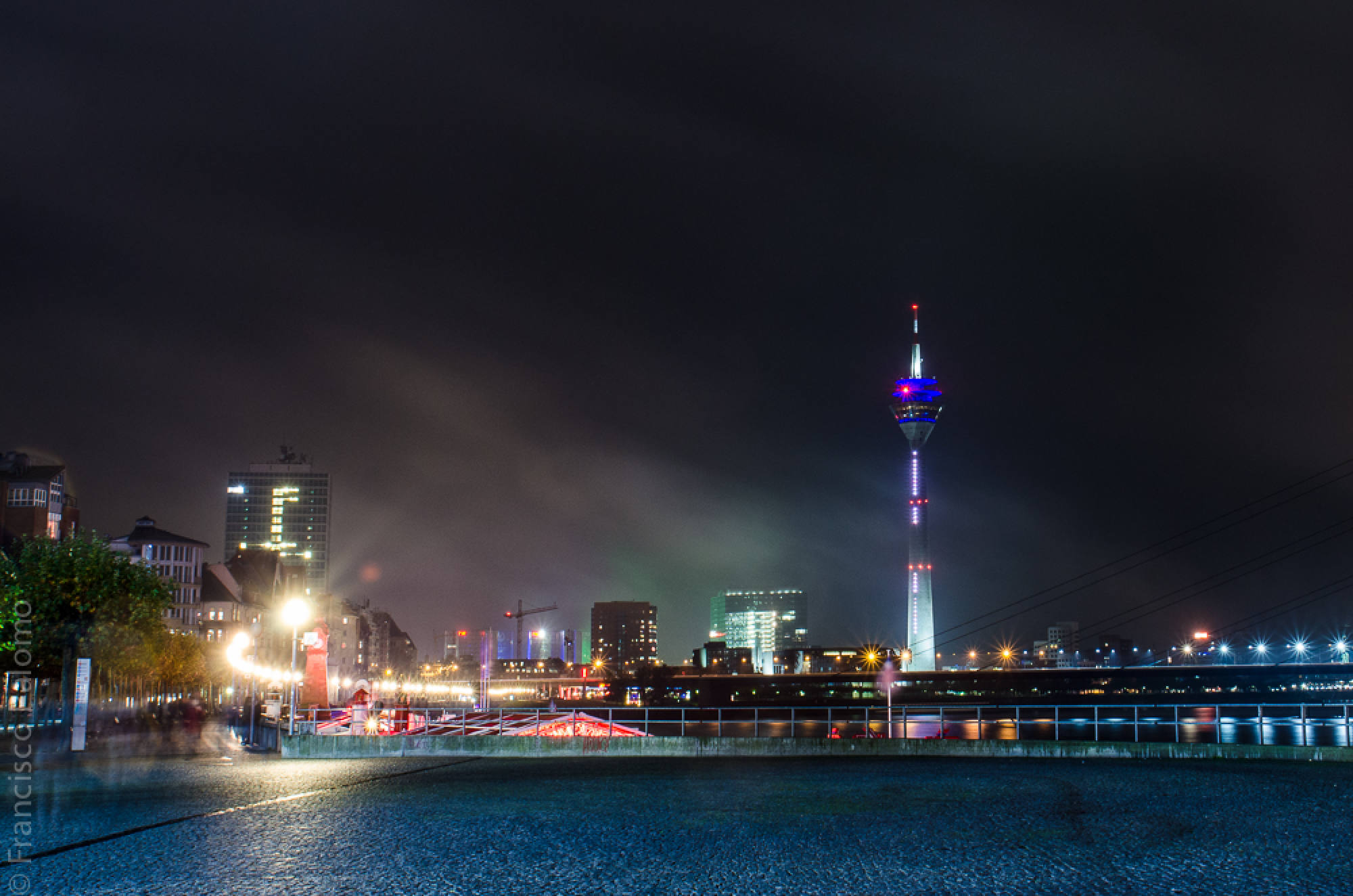 Rheinuferpromenade bei Nacht mit dem beleuchteten Rheinturm